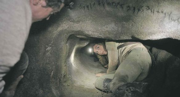Scarlett enters a tunnel underneath the inscription "abandon hope all ye who enter here"